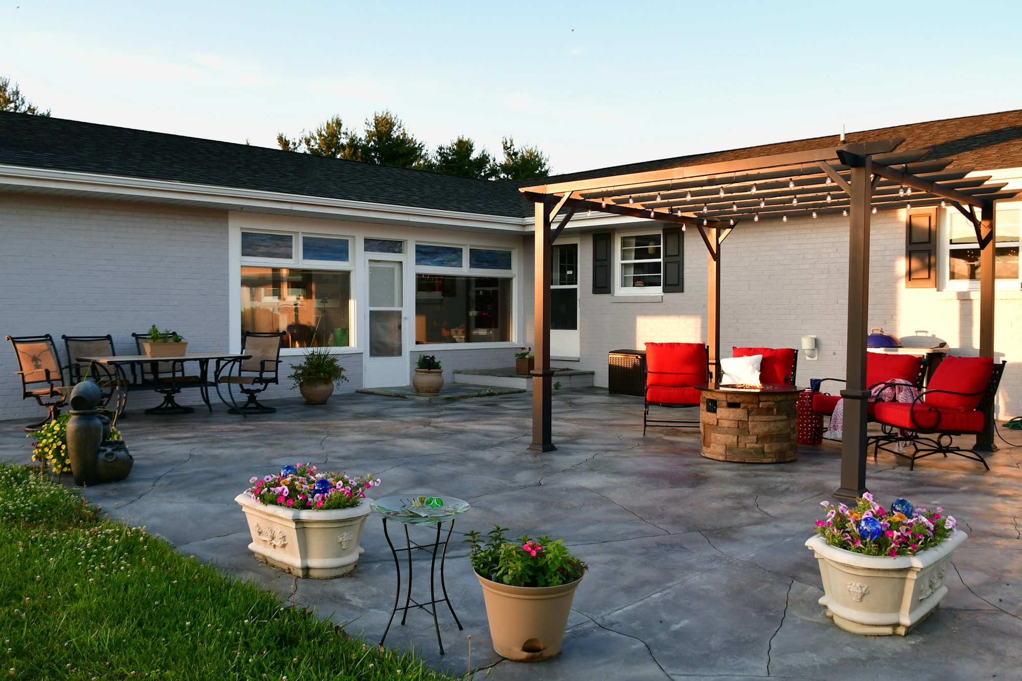 Patio living space with comfortable seating around fire pit under pergola with dining table